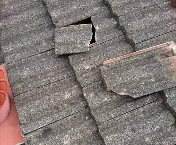 Photo of a grey roof with a highlight picture of a broken piece showing the hole